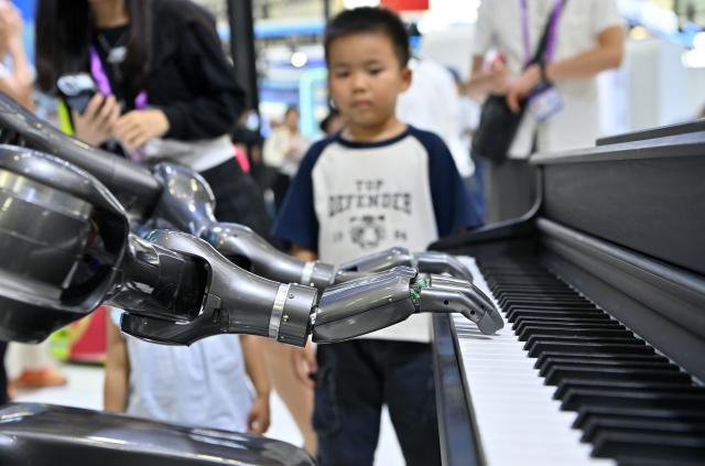(260919) -- NANNING, Sept. 19, 2026 (Xinhua) -- A boy watches a humanoid robot playing the piano at the 23rd China-ASEAN Expo in Nanning, south China's Guangxi Zhuang Autonomous Region, Sept. 19, 2026. Multiple intelligent robots were showcased and demonstrated a variety of skills at the China-ASEAN Expo. (Xinhua/Lu Boan)
