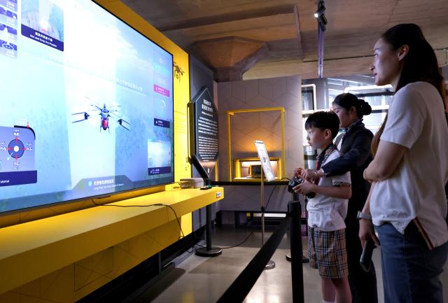 (260919) -- SHANGHAI, Sept. 19, 2026 (Xinhua) -- Visitors play a drone flight simulation game at the WorldSkills Museum in east China's Shanghai, Sept. 19, 2026. With the 48th WorldSkills Competition approaching, the WorldSkills Museum is drawing growing attention. Visitors can learn about the history of the competition and traditional Chinese craftsmanship, and play interactive games based on competition events. (Xinhua/Fang Zhe)