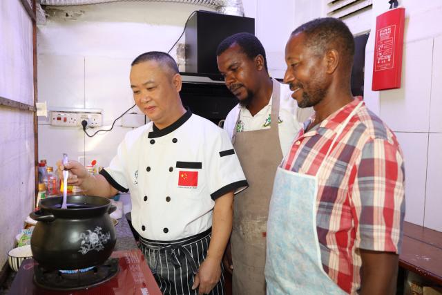 (260919) -- ZANZIBAR, Sept. 19, 2026 (Xinhua) -- Wang Zhongqiang (L), a chef from the 35th Chinese medical team to Zanzibar, teaches two local chefs how to prepare Chinese medicinal chicken soup in Zanzibar, Tanzania, July 29, 2026. TO GO WITH "Feature: Chinese medicinal cuisine brings new inspiration to Tanzanian chef" (The 35th Chinese Medical Team in Zanzibar/Handout via Xinhua)