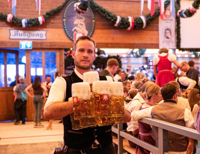 (260919) -- MUNICH, Sept. 19, 2026 (Xinhua) -- A staff member carries cups of beer at the Oktoberfest in Munich, Germany, Sept. 19, 2026. The 191st Oktoberfest, one of the largest folk festivals in Germany, opened on Saturday in Munich, with mayor Dominik Krause tapping the first barrel of beer as a tradition. This year's festival will last until Oct. 4. (Xinhua/Zhang Haofu)