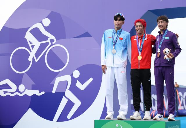 (260920) -- NAGOYA, Sept. 20, 2026 (Xinhua) -- Gold medalist Hojo Takumi (C) of Japan, silver medalist Zhang Xirui (L) of China and bronze medalist Arlan Zhanabay of Kazakhstan pose during the victory ceremony for the men's individual final of triathlon at the 20th Asian Games Aichi-Nagoya 2026 in Gamagori City of Aichi Prefecture, Japan, Sept. 20, 2026. (Xinhua/Deng Hua)