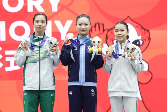 (260921) -- NAGOYA, Sept. 21, 2026 (Xinhua) -- Gold medalist Sham Hui Yu Lydia (C) of China's Hong Kong, silver medalist Sou Cho Man (L) of China's Macao and bronze medalist Eugenia Diva Widodo of Indonesia pose during the victory ceremony for the Women's Changquan of Wushu at the 20th Asian Games Aichi-Nagoya 2026 in Nagoya of Aichi Prefecture, Japan, Sept. 21, 2026. (Xinhua/Long Lei)