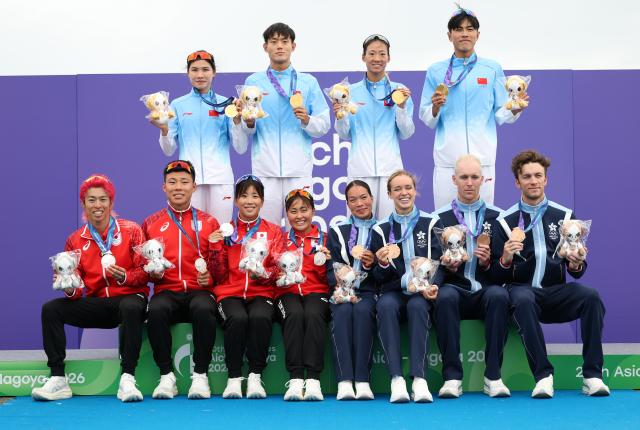 (260921) -- NAGOYA, Sept. 21, 2026 (Xinhua) -- Gold medalists team China (top) pose with silver medalists team Japan (bottom L) and bronze medalists team Hong Kong, China during the victory ceremony for the mixed relay event of triathlon at the 20th Asian Games Aichi-Nagoya 2026 in Gamagori City of Aichi Prefecture, Japan, Sept. 21, 2026. (Xinhua/Deng Hua)