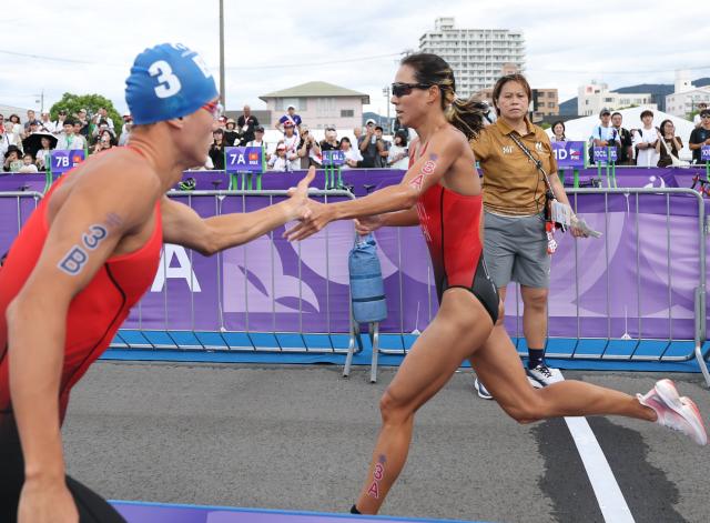 (260921) -- NAGOYA, Sept. 21, 2026 (Xinhua) -- Li Mingxu (L) and Lin Xinyu of team China compete during the mixed relay final of triathlon at the 20th Asian Games Aichi-Nagoya 2026 in Gamagori City of Aichi Prefecture, Japan, Sept. 21, 2026. (Xinhua/Deng Hua)