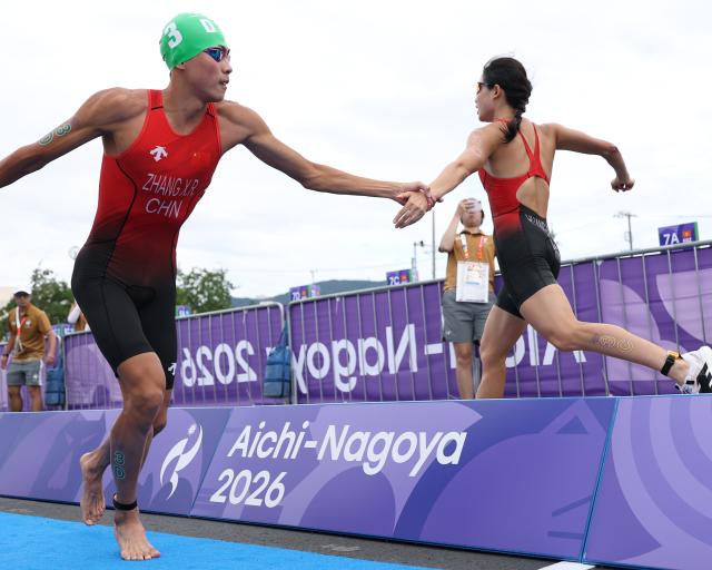 (260921) -- NAGOYA, Sept. 21, 2026 (Xinhua) -- Zhang Xirui (L) and Huang Anqi of team China compete during the mixed relay final of triathlon at the 20th Asian Games Aichi-Nagoya 2026 in Gamagori City of Aichi Prefecture, Japan, Sept. 21, 2026. (Xinhua/Deng Hua)