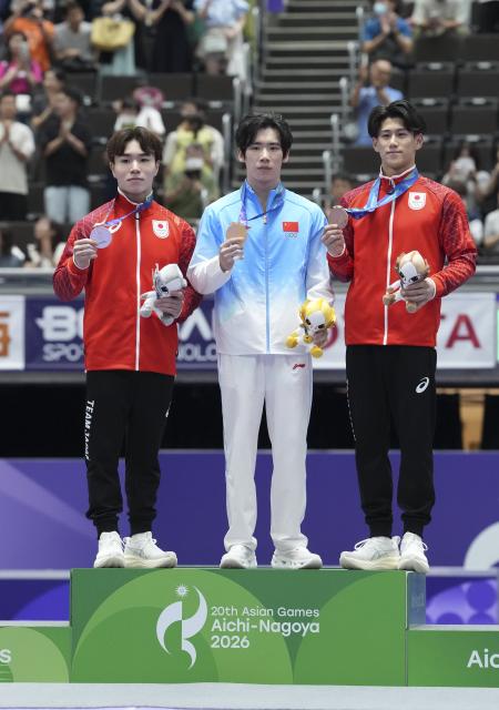 (260921) -- NAGOYA, Sept. 21, 2026 (Xinhua) -- Gold medalist Zhang Boheng (C) of China poses with silver medalist Oka Shinnosuke (L) of Japan and bronze medalist Hashimoto Daiki of Japan during the awarding ceremony for the men's all-around of Artistic Gymnastics at the 20th Asian Games Aichi-Nagoya 2026 in Nagoya, Japan, Sept. 21, 2026. (Xinhua/Lui Siu Wai)