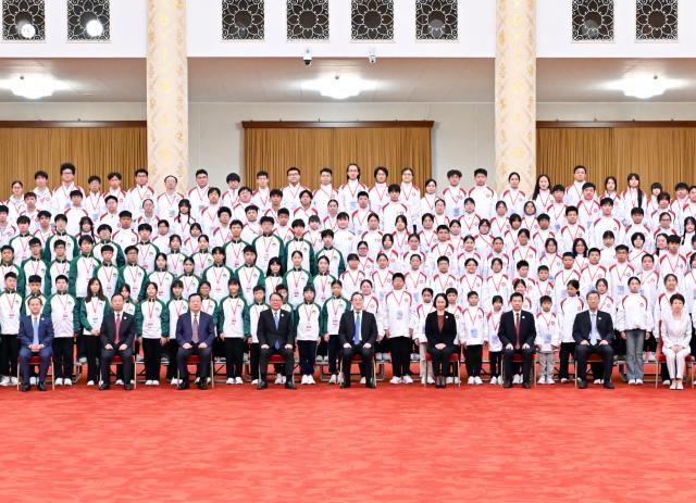 (260921) -- BEIJING, Sept. 21, 2026 (Xinhua) -- Chinese Vice Premier Ding Xuexiang, also a member of the Standing Committee of the Political Bureau of the Communist Party of China Central Committee, meets with a delegation of young representatives from flag-raising teams in Hong Kong and Macao schools and poses for a group photo with them at the Great Hall of the People in Beijing, capital of China, Sept. 21, 2026. (Xinhua/Gao Jie)