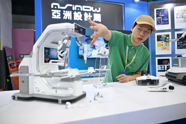 (260921) -- XIONG'AN, Sept. 21, 2026 (Xinhua) -- A merchant introduces an exhibit at the Industrial Design Innovation Achievement Exhibition in Xiong'an New Area, north China's Hebei Province, Sept. 21, 2026. Themed on "Design Empowers, Cluster Rejuvenates," the 2026 Hebei International Industrial Design Week kicked off here on Monday. The Industrial Design Innovation Achievement Exhibition, held during the event, has attracted 340 exhibitors from countries and regions including China, the United States, and Germany, and displayed more than 3,300 outstanding design works, covering innovative products in fields such as intelligent manufacturing, next-generation electronic information technology, robotics, new materials, and smart home. (Xinhua/Mu Yu)