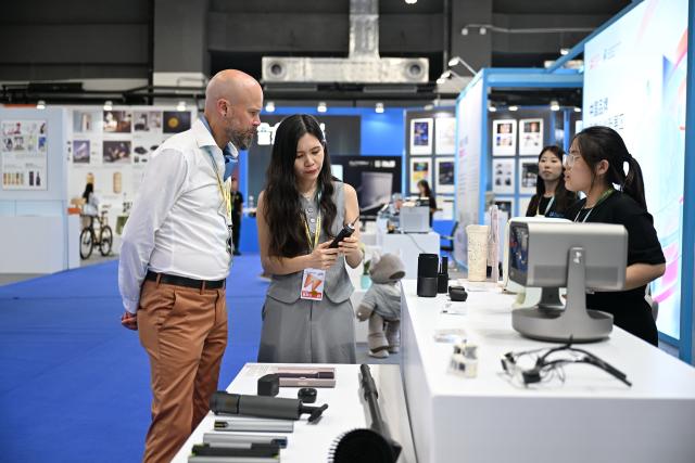 (260921) -- XIONG'AN, Sept. 21, 2026 (Xinhua) -- Foreign merchants visit the Industrial Design Innovation Achievement Exhibition in Xiong'an New Area, north China's Hebei Province, Sept. 21, 2026. Themed on "Design Empowers, Cluster Rejuvenates," the 2026 Hebei International Industrial Design Week kicked off here on Monday. The Industrial Design Innovation Achievement Exhibition, held during the event, has attracted 340 exhibitors from countries and regions including China, the United States, and Germany, and displayed more than 3,300 outstanding design works, covering innovative products in fields such as intelligent manufacturing, next-generation electronic information technology, robotics, new materials, and smart home. (Xinhua/Mu Yu)