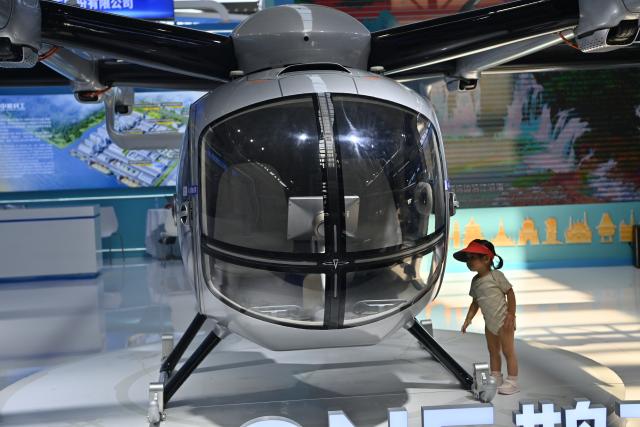 (260921) -- NANNING, Sept. 21, 2026 (Xinhua) -- A child looks at a helicopter at the 23rd China-ASEAN Expo in Nanning, south China's Guangxi Zhuang Autonomous Region, Sept. 21, 2026. The 23rd China-ASEAN Expo features an exhibition area on future space, showcasing equipment such as drones and satellite navigation systems. (Xinhua/Zhou Hua)