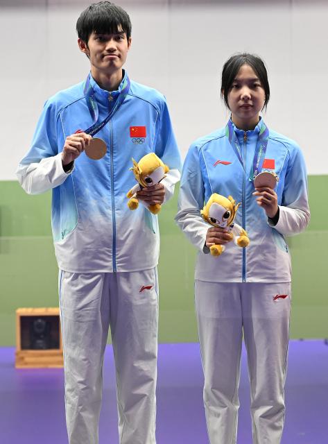 (260922) -- NAGOYA, Sept. 22, 2026 (Xinhua) -- Gold medalists Wang Zifei (R) and Sheng Lihao of team China show their gold medals on the podium during the victory ceremony for the 10m air rifle mixed team of shooting at the 20th Asian Games Aichi-Nagoya 2026 in Toyota of Aichi Prefecture, Japan, Sept. 22, 2026. (Xinhua/Liu Lei)