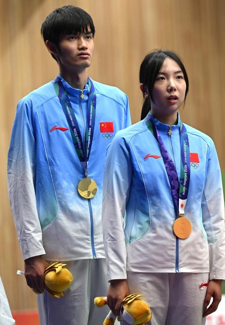 (260922) -- NAGOYA, Sept. 22, 2026 (Xinhua) -- Gold medalists Wang Zifei (R) and Sheng Lihao of team China react on the podium during the victory ceremony for the 10m air rifle mixed team of shooting at the 20th Asian Games Aichi-Nagoya 2026 in Toyota of Aichi Prefecture, Japan, Sept. 22, 2026. (Xinhua/Liu Lei)