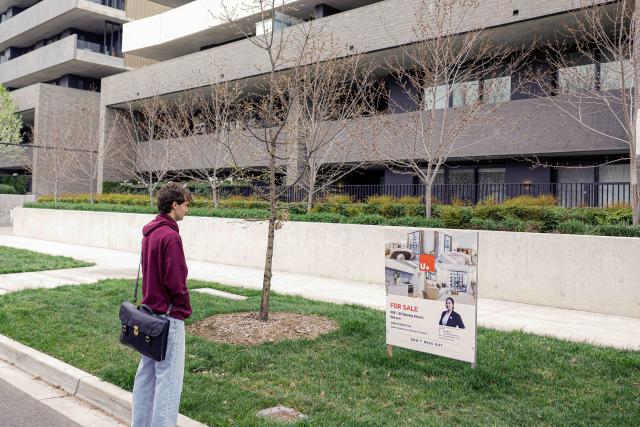 (260922) -- CANBERRA, Sept. 22, 2026 (Xinhua) -- A young man looks at a "for sale" sign in front of a property in Canberra, Australia, on Sept. 22, 2026. TO GO WITH "Younger Australians locked out of housing market: gov't report" (Photo by Chu Chen/Xinhua)