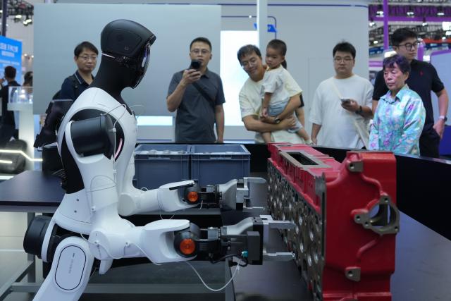 (260922) -- HANGZHOU, Sept. 22, 2026 (Xinhua) -- People learn about a humanoid robot applied to workshop production and assembly during the 2026 Apsara Conference in Hangzhou, east China's Zhejiang Province, Sept. 22, 2026. The 2026 Apsara Conference opened here on Tuesday, and will last for three days. The conference has three main forums and more than 120 sub-forums. (Xinhua/Huang Zongzhi)