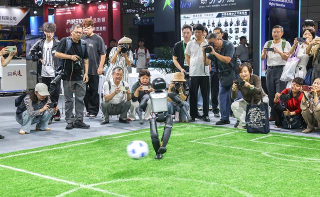 (260922) -- HEFEI, Sept. 22, 2026 (Xinhua) -- Visitors watch a robot playing football at the 2026 World Manufacturing Convention (WMC) in Hefei, east China's Anhui Province, Sept. 21, 2026. The ongoing 2026 WMC showcases wide-ranging applications of robots. (Xinhua/Chang Nengjia)