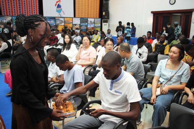 (260923) -- COTONOU, Sept. 23, 2026 (Xinhua) -- A student from the Confucius Institute of the University of Abomey-Calavi distributes mooncakes to attendees during a poetry event celebrating the Mid-Autumn Festival in Cotonou, Benin, Sept. 22, 2026. The Chinese Cultural Center in Benin and the Confucius Institute of the University of Abomey-Calavi jointly held the event here on Tuesday. (Photo by Seraphin Zounyekpe/Xinhua)