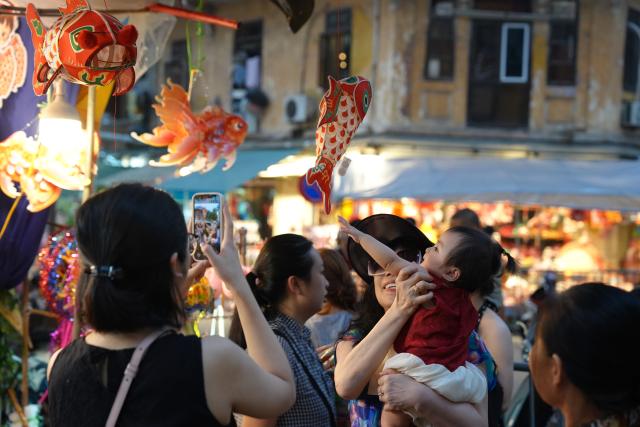 (260923) -- HANOI, Sept. 23, 2026 (Xinhua) -- A child touches a fish-shaped lantern at the Old Quarter in Hanoi, Vietnam, Sept. 22, 2026. A festive atmosphere is growing here as the Mid-Autumn Festival approaches. (Xinhua/Liu Ying)