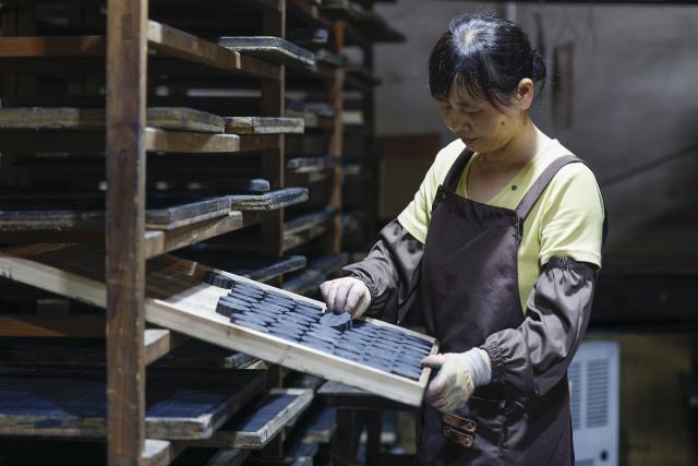 (260923) -- HUANGSHAN, Sept. 23, 2026 (Xinhua) -- A craftswoman airs mooncake-shaped Hui ink sticks at an ink workshop in Shexian County, Huangshan City, east China's Anhui Province, Sept. 9, 2026.
  The Hui ink sticks are primarily composed of the soot produced by burning pine trees or tung oil, with glue as the main ingredient, supplemented by various minerals and Chinese herbal ingredients in the formulation. It undergoes a meticulous crafting process involving dozens of steps.
  As the Mid-Autumn Festival approaches, local ink-making craftsmen shaped ink sticks into mooncake forms, giving the ancient craft a trendy way to greet the festival. (Photo by Shi Yalei/Xinhua)