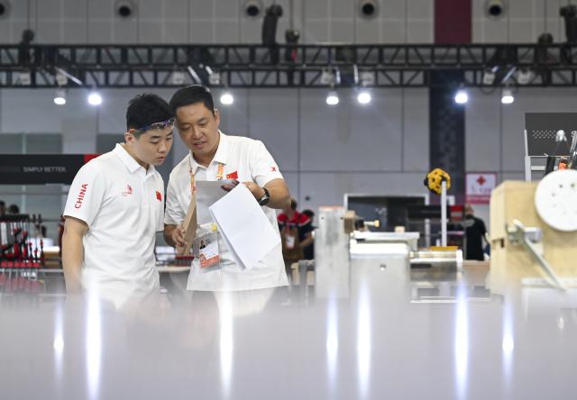 (260923) -- SHANGHAI, Sept. 23, 2026 (Xinhua) -- A contestant (L) talks with an expert in the cabinetmaking event during the 48th WorldSkills Competition in east China's Shanghai, Sept. 23, 2026. The competition kicks off at the National Exhibition and Convention Center here on Wednesday. (Xinhua/Chen Haoming)