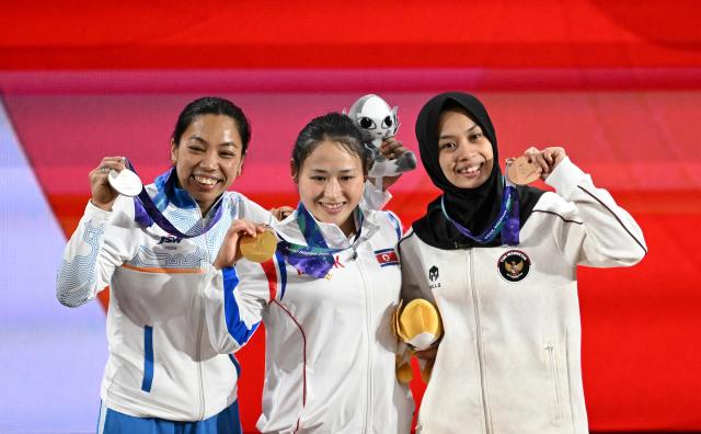 (260923) -- NAGOYA, Sept. 23, 2026 (Xinhua) -- Gold medalist Ri Song Gum of the Democratic People's Republic of Korea (C) , silver medalist Mirabai Chanu Saikhom of India (L) and bronze medalist Luluk Diana Tri Wijayana of Indonesia celebrate during the awarding ceremony for the women's 49kg final of weightlifting at the 20th Asian Games Aichi-Nagoya 2026 in Nagoya, Japan, Sept. 23, 2026. (Xinhua/Yu Yang)