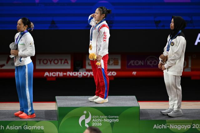 (260923) -- NAGOYA, Sept. 23, 2026 (Xinhua) -- Gold medalist Ri Song Gum of the Democratic People's Republic of Korea (C) , silver medalist Mirabai Chanu Saikhom of India (L) and bronze medalist Luluk Diana Tri Wijayana of Indonesia react during the awarding ceremony for the women's 49kg final of weightlifting at the 20th Asian Games Aichi-Nagoya 2026 in Nagoya, Japan, Sept. 23, 2026. (Xinhua/Yu Yang)