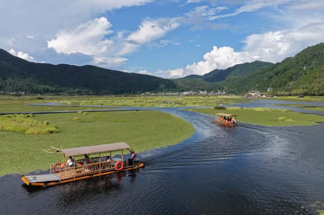 (260923) -- BAOSHAN, Sept. 23, 2026 (Xinhua) -- A drone photo taken on Sept. 22, 2026 shows tourists taking a boat ride at a wetland park in Baoshan City, southwest China's Yunnan Province. In recent years, Baoshan City has developed distinctive industries such as homestays, camping, dendrobium cultivation and tea. The city is leveraging ecological tourism and cultural resources to advance rural revitalization, injecting new vitality into the high-quality development of its cultural and tourism industries. (Photo by Gong Zujin/Xinhua)