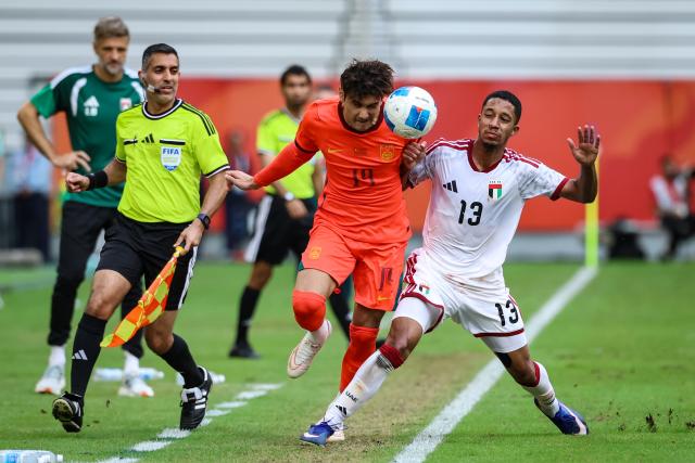 (260923) -- TOYOTA, Sept. 23, 2026 (Xinhua) -- Baihelamu Abuduwaili (L) of China vies with Yousif Almarzooqi of the United Arab Emirates during the group B match of Men's Football between China and the United Arab Emirates at 20th Asian Games Aichi-Nagoya 2026 in Toyota, Japan, Sept. 23, 2026. (Xinhua/Jia Haocheng)