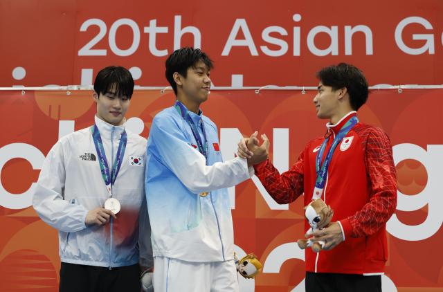 (260923) -- TOKYO, Sept. 23, 2026 (Xinhua) -- Gold medalist Zhang Zhanshuo (C) of China, silver medalist Hwang Sunwoo (L) of South Korea and bronze medalist Murasa Tatsuya of Japan react during the awarding ceremony for the men's 200m freestyle at the 20th Asian Games Aichi-Nagoya 2026 in Tokyo, Japan, Sept. 23, 2026. (Xinhua/Wu Zhizun)
