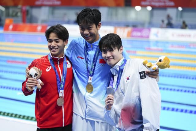 (260923) -- TOKYO, Sept. 23, 2026 (Xinhua) -- Gold medalist Zhang Zhanshuo (C) of China, silver medalist Hwang Sunwoo (R) of South Korea and bronze medalist Murasa Tatsuya of Japan pose after the awarding ceremony for the men's 200m freestyle at the 20th Asian Games Aichi-Nagoya 2026 in Tokyo, Japan, Sept. 23, 2026. (Xinhua/Chen Zeguo)