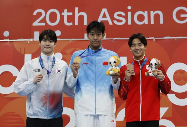 (260923) -- TOKYO, Sept. 23, 2026 (Xinhua) -- Gold medalist Zhang Zhanshuo (C) of China, silver medalist Hwang Sunwoo (L) of South Korea and bronze medalist Murasa Tatsuya of Japan pose during the awarding ceremony for the men's 200m freestyle at the 20th Asian Games Aichi-Nagoya 2026 in Tokyo, Japan, Sept. 23, 2026. (Xinhua/Wu Zhizun)