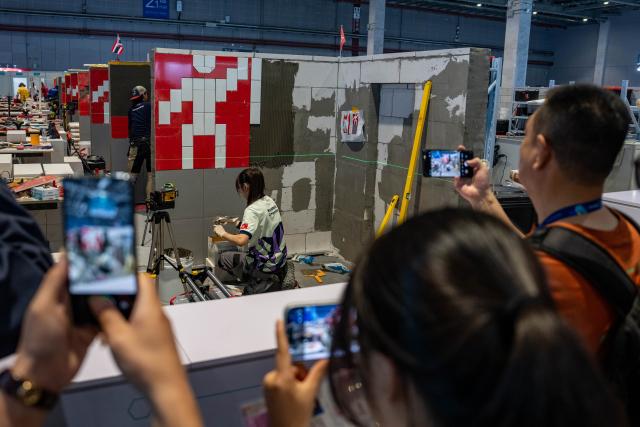 (260923) -- SHANGHAI, Sept. 23, 2026 (Xinhua) -- People watch a contestant participating in the wall and floor tiling event during the 48th WorldSkills Competition in east China's Shanghai, Sept. 23, 2026. The competition events started at the National Exhibition and Convention Center (Shanghai) on Wednesday. (Xinhua/Zhang Xiaoyu)