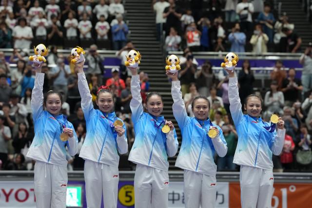 (260923) -- NAGOYA, Sept. 23, 2026 (Xinhua) -- Gold medalists Zhang Yihan, Ke Qinqin, Du Siyu, Zhang Qingying, Qiu Qiyuan (L-R) of team China pose on the podium during the awarding ceremony of the women's team final of Artistic Gymnastics at the 20th Asian Games Aichi-Nagoya 2026 in Nagoya, Japan, Sept. 23, 2026. (Xinhua/Lui Siu Wai)