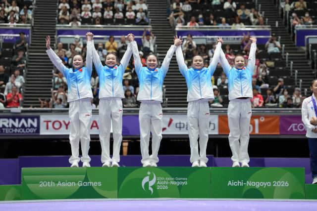 (260923) -- NAGOYA, Sept. 23, 2026 (Xinhua) -- Gold medalists Zhang Yihan, Ke Qinqin, Du Siyu, Zhang Qingying, Qiu Qiyuan (L-R) of team China step on the podium during the awarding ceremony of the women's team final of Artistic Gymnastics at the 20th Asian Games Aichi-Nagoya 2026 in Nagoya, Japan, Sept. 23, 2026. (Xinhua/Lui Siu Wai)