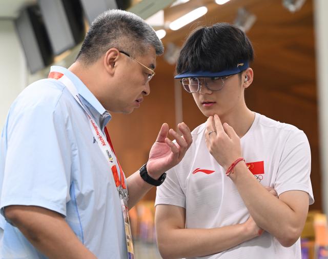 (260924) -- TOYOTA, Sept. 24, 2026 (Xinhua) -- Bu Shuaihang (R) of China talks with his coach during the 10m Air Pistol Men Team Final of shooting at the 20th Asian Games Aichi-Nagoya 2026 in Toyota of Aichi Prefecture, Japan, Sept. 24, 2026. (Xinhua/Liu Lei)