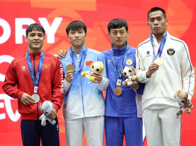 (260924) -- NAGOYA, Sept. 24, 2026 (Xinhua) -- Gold medalist Ou Jiaming (2nd L) of China, silver medalist Dinh Van Tam (1st L) of Vietnam and bronze medalists Saydullo Abdurashitov (2nd R) of Uzebkhstan and Fereddy Sinaga of Indonesia pose during the victory ceremony for the men's 56kg of Wushu at the 20th Asian Games Aichi-Nagoya 2026 in Nagoya, Japan, Sept. 24, 2026. (Xinhua/Long Lei)