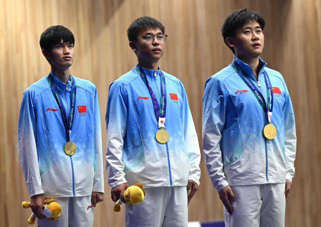 (260925) -- TOYOTA, Sept. 25, 2026 (Xinhua) -- Gold medalists Liu Yukun, Zhang Changhong, Sheng Lihao (from R to L) of team China react during the victory ceremony for the 50m rifle 3 positions men team of shooting at the 20th Asian Games Aichi-Nagoya 2026 in Toyota of Aichi Prefecture, Japan, Sept. 25, 2026. (Xinhua/Liu Lei)