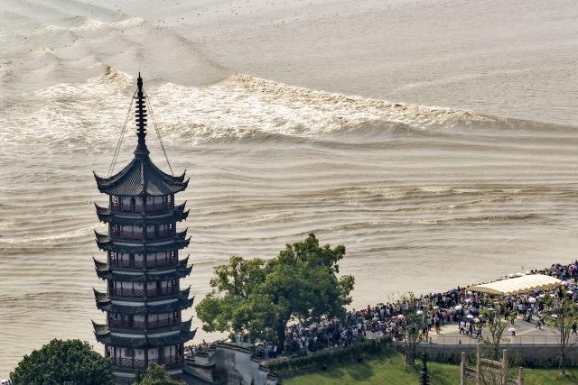 (260925) -- HAINING, Sept. 25, 2026 (Xinhua) -- A drone photo taken on Sept. 25, 2026 shows people viewing the tidal bore of the Qiantang River at a park in Haining City, east China's Zhejiang Province. The Mid-Autumn Festival falls on Sept. 25 this year. Tourists came to the Yanguan section of the Qiantang River, the best tide-watching resort, to watch the tide during the best tide-viewing period. (Photo by Wang Zhenyu/Xinhua)