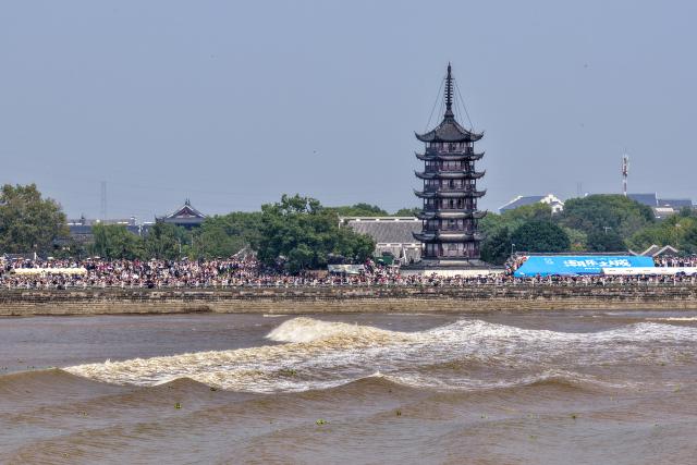 (260925) -- HAINING, Sept. 25, 2026 (Xinhua) -- A drone photo taken on Sept. 25, 2026 shows people viewing the tidal bore of the Qiantang River at a park in Haining City, east China's Zhejiang Province. The Mid-Autumn Festival falls on Sept. 25 this year. Tourists came to the Yanguan section of the Qiantang River, the best tide-watching resort, to watch the tide during the best tide-viewing period. (Photo by Wang Zhenyu/Xinhua)