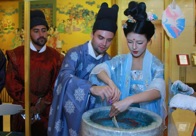 (260925) -- BEIJING, Sept. 25, 2026 (Xinhua) -- Foreign tourists dressed in Hanfu learn to make lacquer fans at a restaurant in Xi'an, northwest China's Shaanxi Province, Sept. 23, 2026. TO GO WITH "China Focus: Same moon, shared stories: Foreigners find reunion in China's Mid-Autumn Festival" (Xinhua)