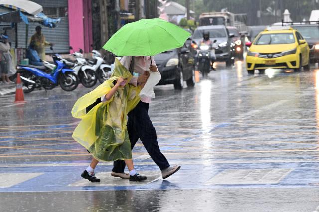 (260925) -- BANGKOK, Sept. 25, 2026 (Xinhua) -- Pedestrians cross a street in the rain in Bangkok, Thailand, on Sept. 25, 2026. The Thai Meteorological Department has issued a warning of heavy rain in Greater Bangkok and other provinces across Thailand, due to a strong low-pressure system combined with seasonal monsoon patterns. (Xinhua/Rachen Sageamsak)