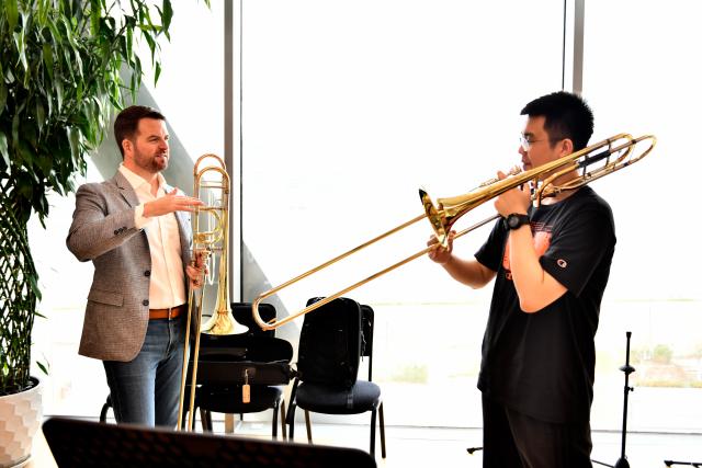(260926) -- TIANJIN, Sept. 26, 2026 (Xinhua) -- This undated file photo shows Lee Allen (L) teaching a student at the Tianjin Juilliard School in Tianjin, north China.
  Lee Allen, a U.S. trombonist, joined the Tianjin Juilliard School as one of its first resident faculty members in 2019. 
  In 2017, while still teaching in the U.S. state of Ohio, Allen led five students on a month-long tour across China, covering 17 cities and staging 19 concerts. This immersive experience gave him deep insight into China's thriving artistic landscape. He noted that the abundance of opportunities, strong institutional support for the arts, and Tianjin's livable urban environment convinced him to build his long-term career here. 
  Over the years, Allen has dedicated himself to nurturing young musical talent, with generations of his students going on to perform on leading international stages. His two children were both born and raised in Tianjin, making the city a true family home. 
  This year, the Tianjin Juilliard School formed its first all-faculty brass quintet, a rare opportunity that allows Allen to perform alongside his peers and deepen his artistic practice. 
  For Allen, music bridges different civilizations, and the Tianjin Juilliard School is a dynamic platform for exchange between Chinese and U.S. arts education. "Teaching is a two-way journey of growth," he said. "While I guide my students, they also teach me every day." (Xinhua)