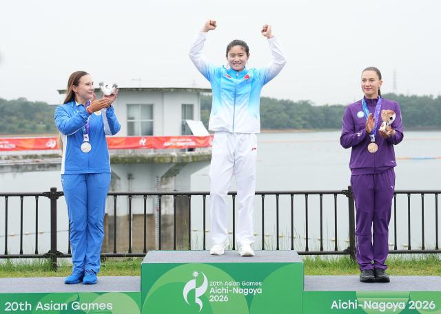 (260926) -- NAGOYA, Sept. 26, 2026 (Xinhua) -- Gold medalist Wang Nan (C) of China celebrates as silver medalist Arina Tanatmisheva (L) of Uzbekistan and bronze medalist Stella Sukhanova of Kazakhstan cheer for her during the victory ceremony for the women's kayak single 500m of canoe sprint at the 20th Asian Games Aichi-Nagoya 2026 in Miyoshi of Aichi Prefecture, Japan, Sept. 26, 2026. (Xinhua/Zhang Haobo)