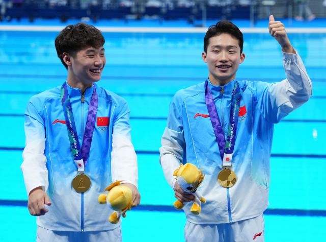 (260926) -- TOKYO, Sept. 26, 2026 (Xinhua) -- Gold medalists Wang Zongyuan (R)/Zheng Jiuyuan react after the victory ceremony for the men's synchronised 3m springboard of diving at the 20th Asian Games Aichi-Nagoya 2026 in Tokyo, Japan, Sept. 26, 2026. (Xinhua/Chen Zeguo)