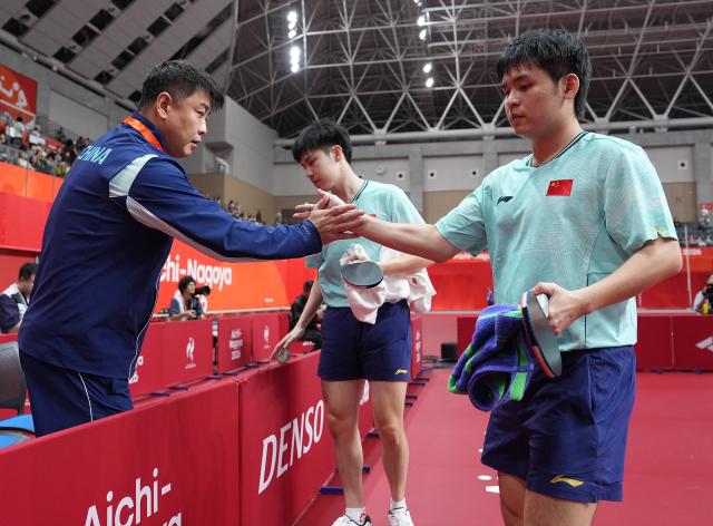 (260927) -- TOYOTA, Sept. 27, 2026 (Xinhua) -- Huang Youzheng (C)/Lin Shidong (R) of China greet their coach Wang Hao after the men's doubles semifinal table tennis match between Huang Youzheng/Lin Shidong of China and Matsushima Sora/Togami Shunsuke of Japan at the 20th Asian Games Aichi-Nagoya 2026 in Toyota of Aichi Prefecture, Japan, Sept. 27, 2026. (Xinhua/Cheong Kam Ka)