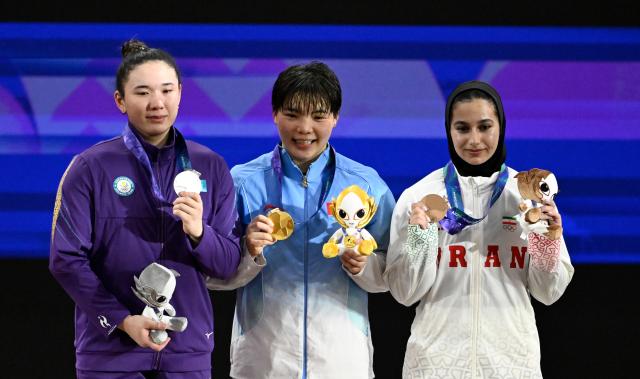 (260927) -- NAGOYA, Sept. 27, 2026 (Xinhua) -- Gold medalist He Renxiu (C) of China, silver medalist Ayanat Zhumagali (L) of Kazakhstan and bronze medalist Reihaneh Karimi of Iran pose during the awarding ceremony after the women's 77kg final of weightlifting at the 20th Asian Games Aichi-Nagoya 2026 in Nagoya, Japan, Sept. 27, 2026. (Xinhua/Yu Yang)