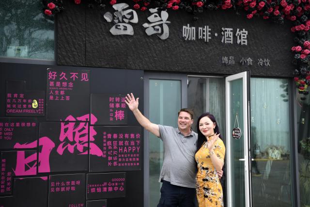 (260928) -- RIZHAO, Sept. 28, 2026 (Xinhua) -- Ryan Norman and his wife Zhang Lei wave hands outside their cafe in Rizhao, east China's Shandong Province, Sept. 24, 2026.
  Ryan Norman, from the U.S. state of California, has lived in Rizhao for 20 years. He married a Chinese woman and regards Rizhao as his second home. For more than three years, he has been sharing daily life in the city through short videos. His videos have attracted more than 5 million followers across social media platforms, earning him the nickname "Lei Ge," or "Brother Lei," among Chinese netizens.
  Beyond his work on social media, Norman runs several businesses, including a cafe and a chicken restaurant. He is also a fan of both Sichuan and Shandong cuisines and especially loves spicy food, joking that he has developed a "Chinese stomach."
  For Norman, the opportunities brought by China's development and the warmth he finds in everyday life are key reasons he has chosen to stay. He hopes to use his videos and personal experience to help foster greater understanding and friendship between people in China and the United States.
  In Norman's view, the Chinese market is a large platform, and the rapid development of China's economy has brought tremendous opportunities to merchants and enterprises all over the world. (Xinhua/Guo Xulei)