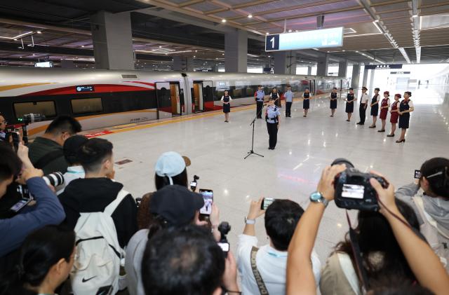 (260928) -- XI'AN, Sept. 28, 2026 (Xinhua) -- Train attendants are seen beside G9997, the first train of the Xi'an-Ankang high-speed railway, at Xi'an East Railway Station in Xi'an, northwest China's Shaanxi Province, Sept. 28, 2026. The Xi'an-Ankang high-speed railway was officially put into operation on Monday, cutting the railway travel time between Xi'an and Ankang to less than one hour. Spanning about 171 kilometers and with a design speed of 350 kilometers per hour, the railway runs through the cities of Xi'an, Shangluo and Ankang in Shaanxi Province and has five stations along the line. (Xinhua/Li Yibo)