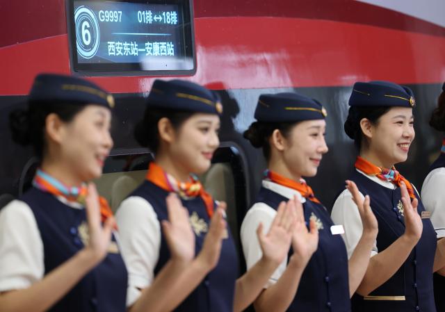 (260929) -- BEIJING, Sept. 29, 2026 (Xinhua) -- Train attendants wave hands beside G9997, the first train of the Xi'an-Ankang high-speed railway, at Xi'an East Railway Station in Xi'an, northwest China's Shaanxi Province, Sept. 28, 2026. The Xi'an-Ankang high-speed railway was officially put into operation on Monday. (Xinhua/Li Yibo)