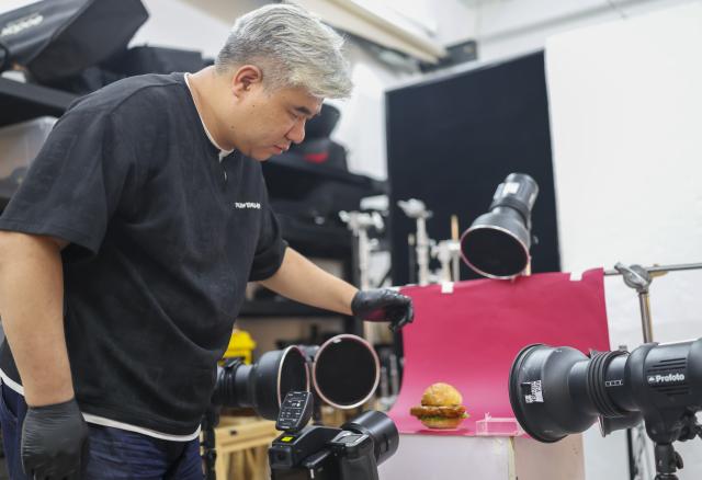 (260929) -- SHANGHAI, Sept. 29, 2026 (Xinhua) -- Li Haohan prepares to take photos of a hamburger at his studio in Shanghai, east China, Sept. 24, 2026. Unlike chefs who prioritize flavor, food stylists handle various ingredients, arrange plates and use tools to create the desired visual effects, capturing food's most appealing moments.
   Li Haohan has been engaged in food styling for more than 20 years. 
Li used to be a pastry chef. In 2003, he was invited to participate in a commercial shoot on instant noodles, where his outstanding craftsmanship earned him recognition. Since then, Li started to work as a part-time food stylist.
   In 2010, Li became a professional food stylist and founded a food styling studio. Today, his team has grown to over 20 members, forming a professional team with deep expertise in food styling in China. (Xinhua/Chen Haoming)