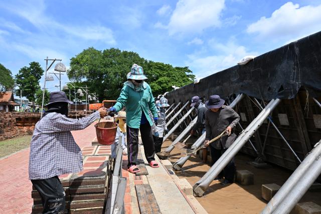 (260929) -- AYUTTHAYA, Sept. 29, 2026 (Xinhua) -- Workers install flood barriers to protect Wat Chaiwatthanaram from flooding in Ayutthaya, Thailand, Sept. 29, 2026. Thailand's Department of Disaster Prevention and Mitigation reported that, as of the evening of Sept. 28, flooding since Sept. 16 had killed 23 people nationwide and affected more than 2.5 million others. (Xinhua/Rachen Sageamsak)